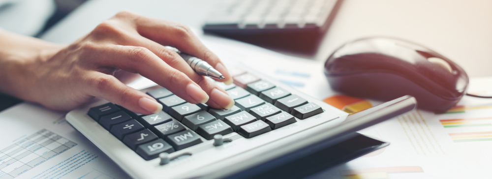 Closeup of a person's hand on a calculator as they calculate accident damages