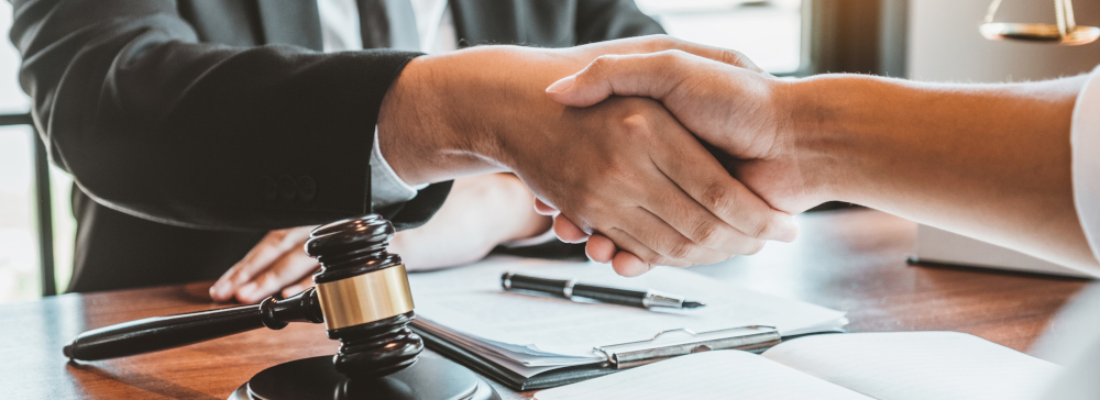 A lawyer shaking hands with a client over a desk after a successful accident case settlement
