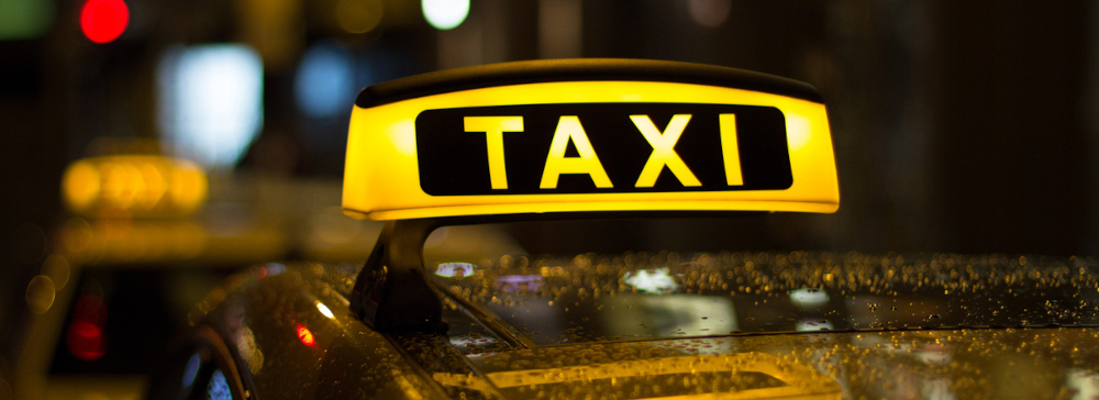 A yellow taxi sign on top of a car at night in the city