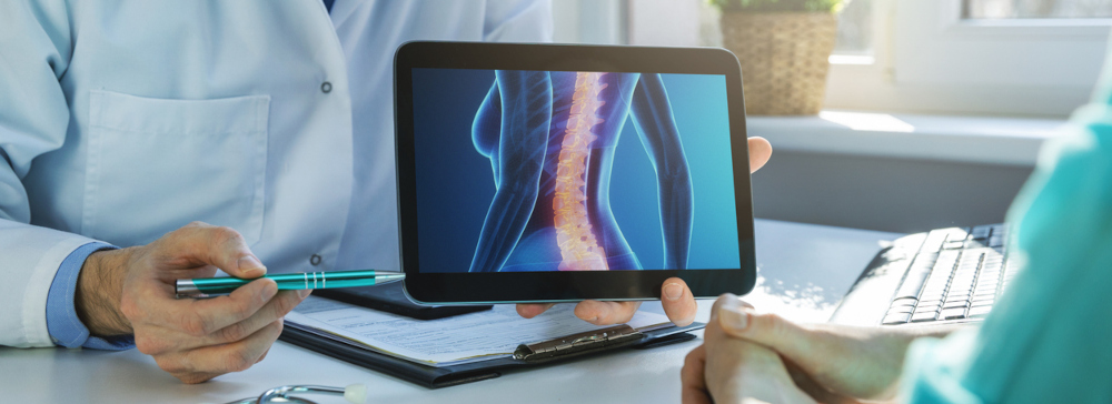 A doctor diagnosing a back injury on a tablet