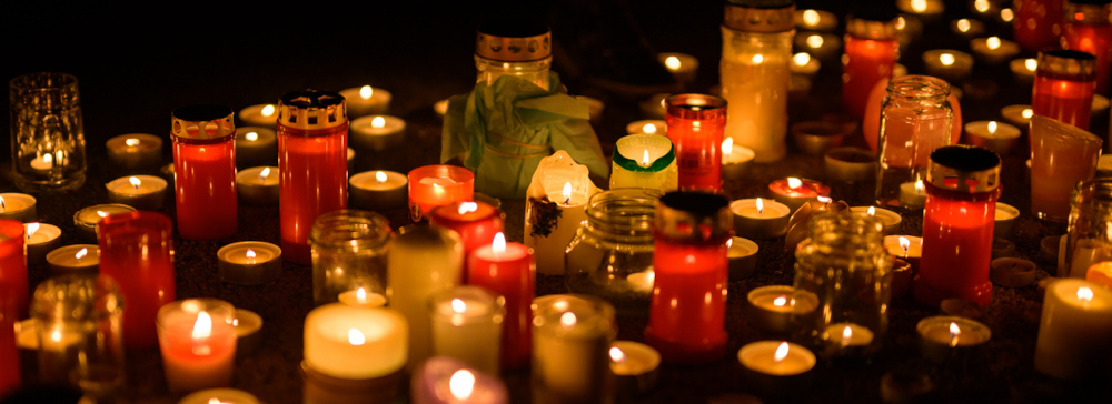 Many candles burning on the ground after a memorial service for a wrongful death
