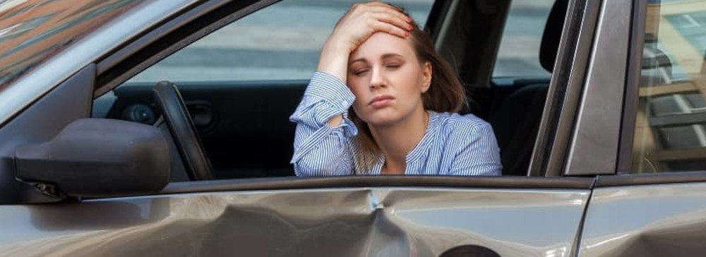 A woman with her hand on her forehead in a car after a car accident