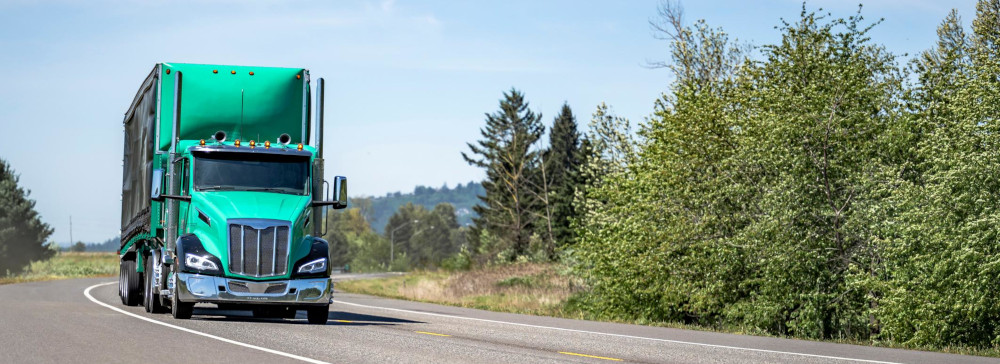 A green semi truck driving down the interstate