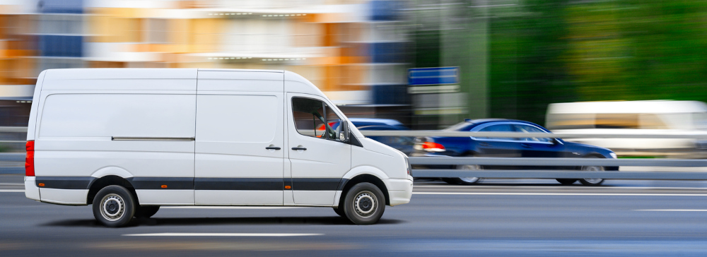 White delivery van speeding in city traffic