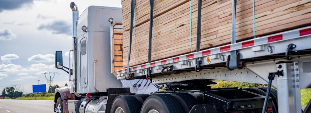 A heavily loaded truck with lumber tied down on the cargo bed