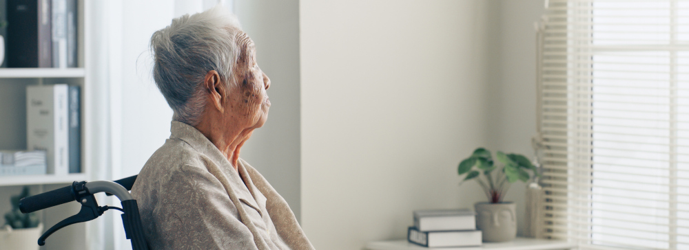 Lonely senior in a nursing home looking out the window
