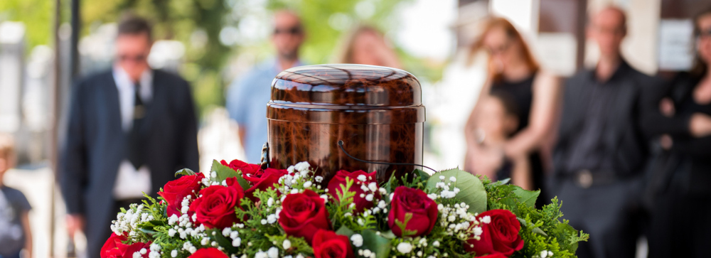 A funeral urn and flowers at a funeral with family members in the background after a wrongful death