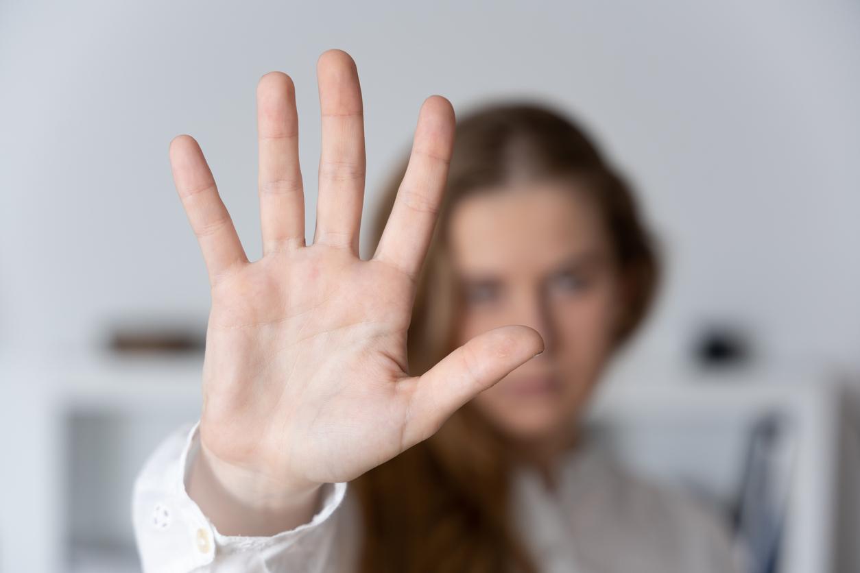 A woman holding an outstretched hand toward the camera in a "stop" gesture, symbolizing sexual abuse
