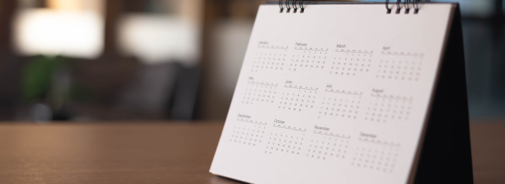A desktop calendar on a desk showing several months