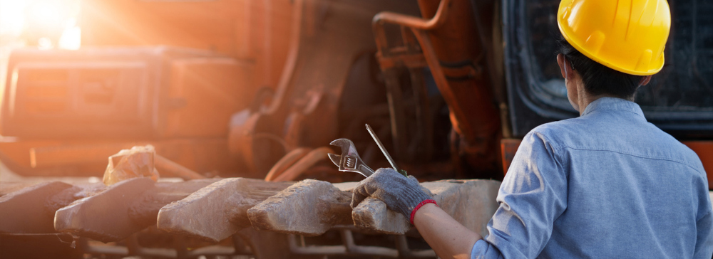 A construction worker in a hard hat in front of a front end loader.