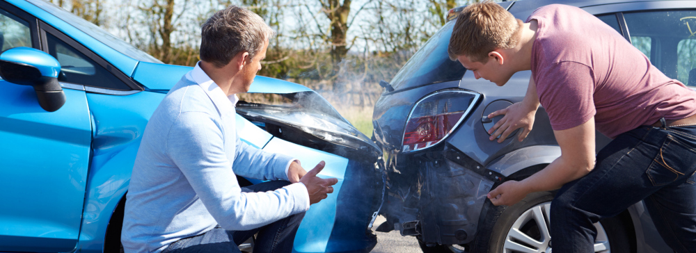 Two drivers looking at the damage to their vehicles after a rear end collision.