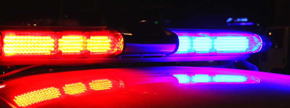 Flashing red and blue light bar on top of a police car at night.