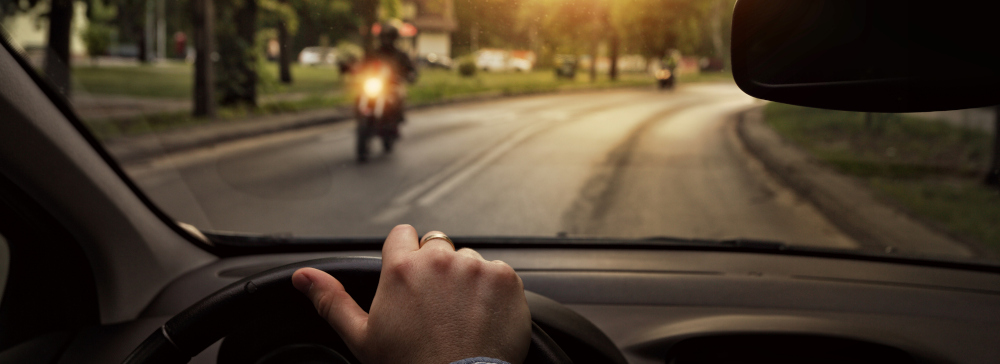 View from the drivers seat of a motorcycle passing a car in oncoming traffic
