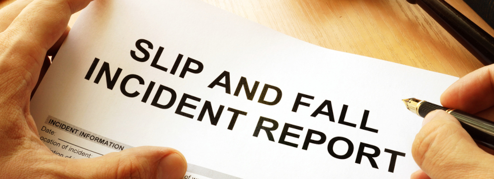 A person filling out a form labeled Slip and Fall Accident Report