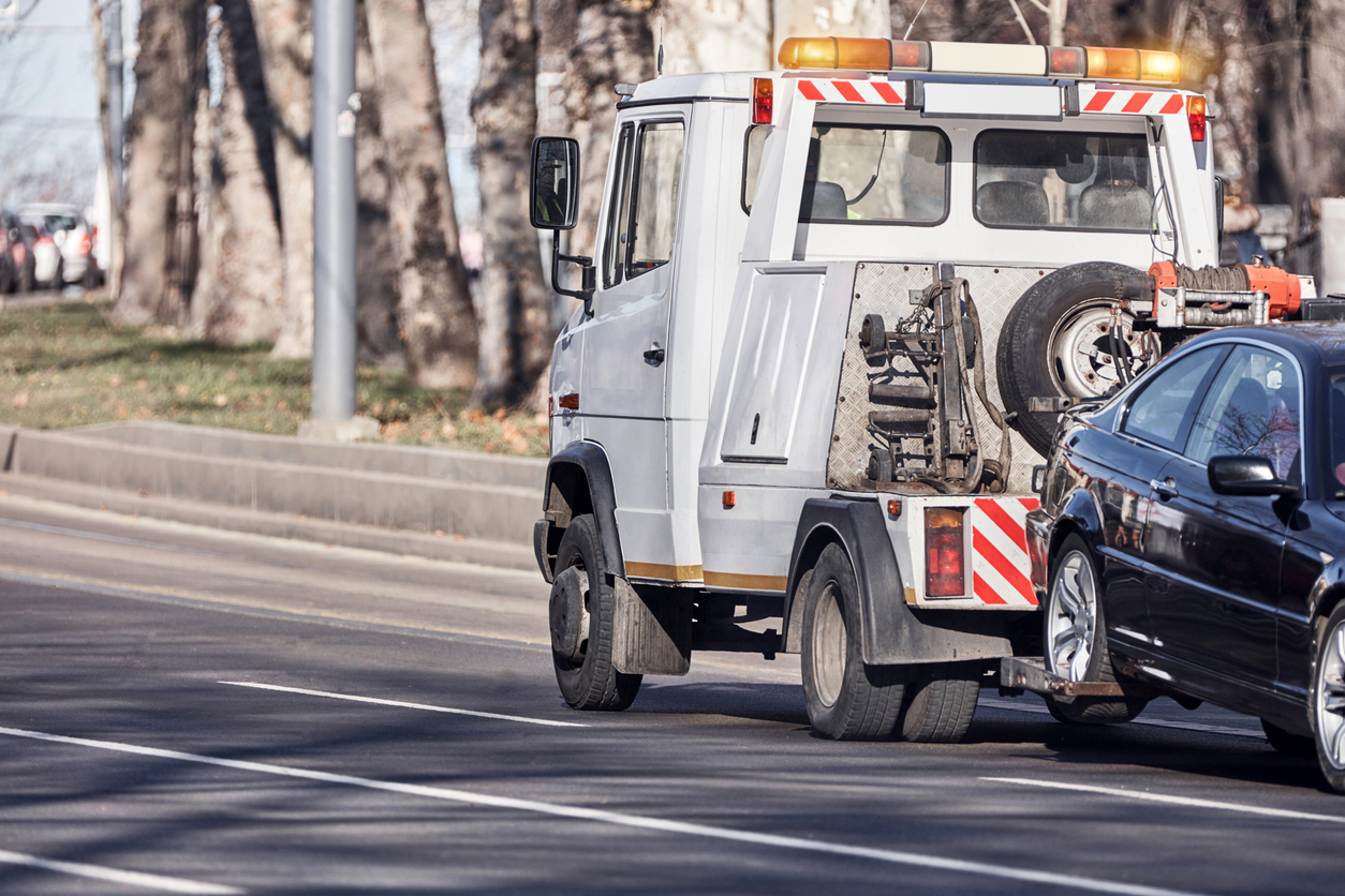 An auto repossession in progress with a tow truck towing a repossessed car away